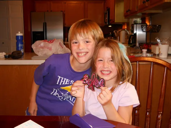 Two smiling children enjoying time together in a kitchen.