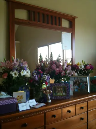 A wooden dresser with a large mirror adorned with various flower arrangements.