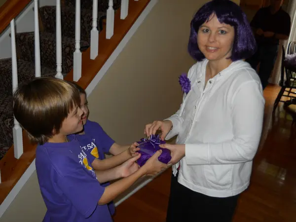 Woman with purple hair and a boy in purple shirt holding a purple toy.