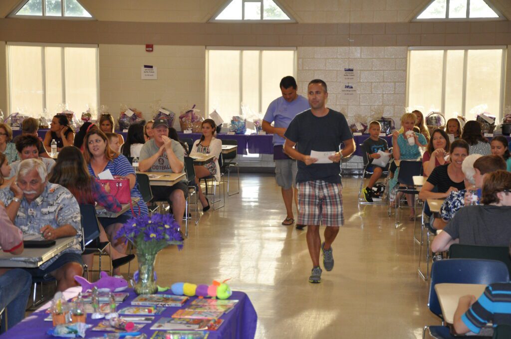 Man walking down aisle at a community event with seated attendees.