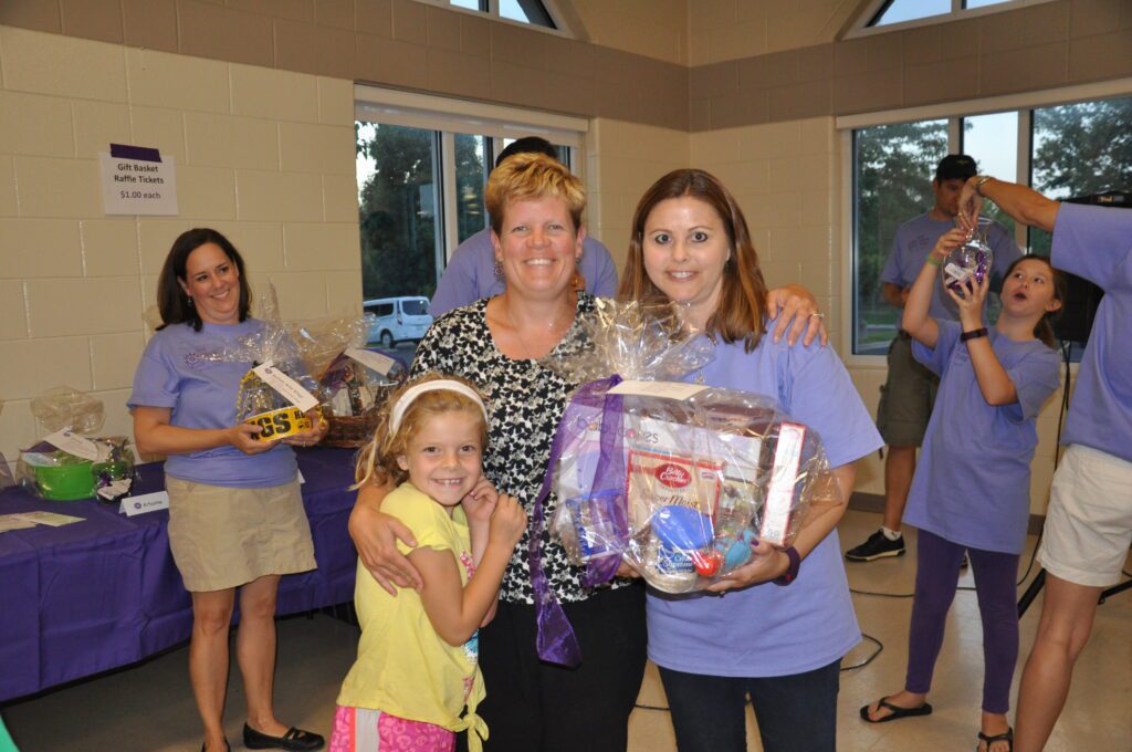 Three women and a young girl holding gift baskets inside a room.