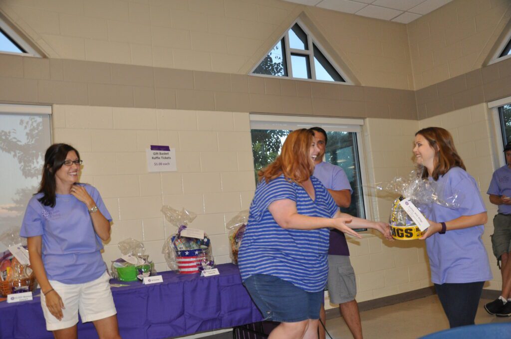 People exchanging items in a casual indoor setting with a table of goods.