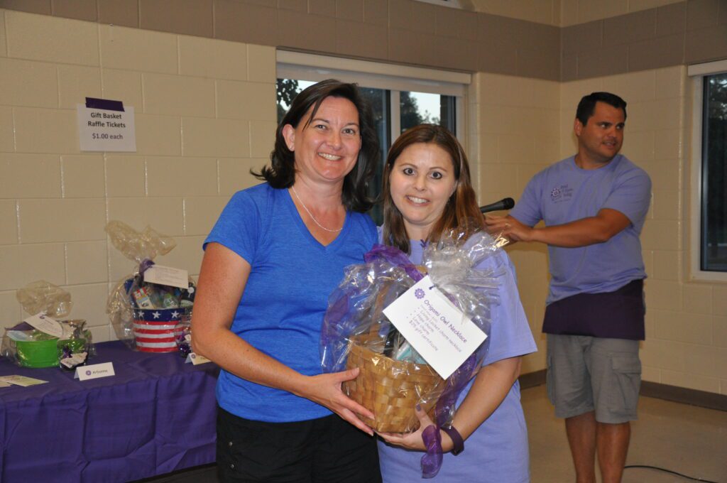 Two women posing with a gift basket indoors.