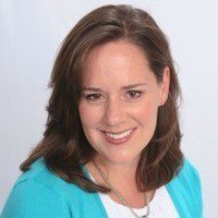 Professional headshot of a smiling woman with brown hair wearing a turquoise top.